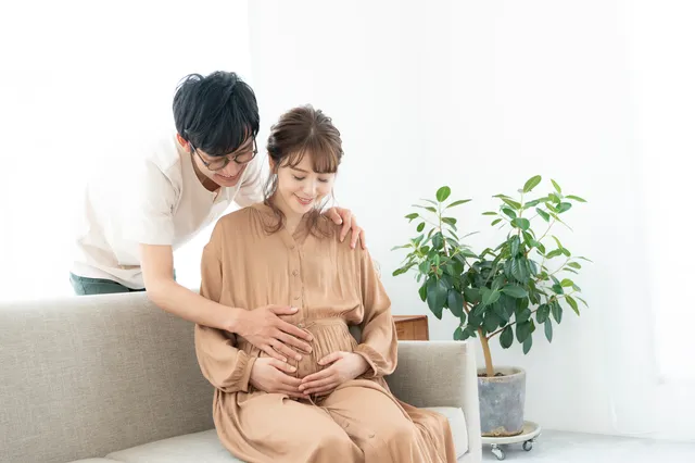 お腹をなでる妊婦と夫