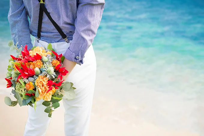 海で花を持つ男性の後ろ姿