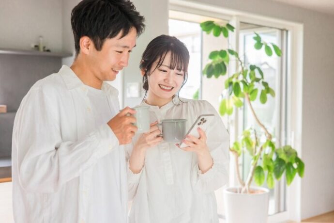 スマホを見ながら笑顔で会話する夫婦
