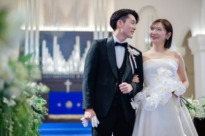 チャペルで腕を組んで微笑む新郎新婦_アニヴェルセル 江坂