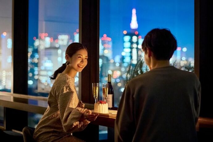 夜景の見えるレストランで食事するカップル_アニヴェルセル