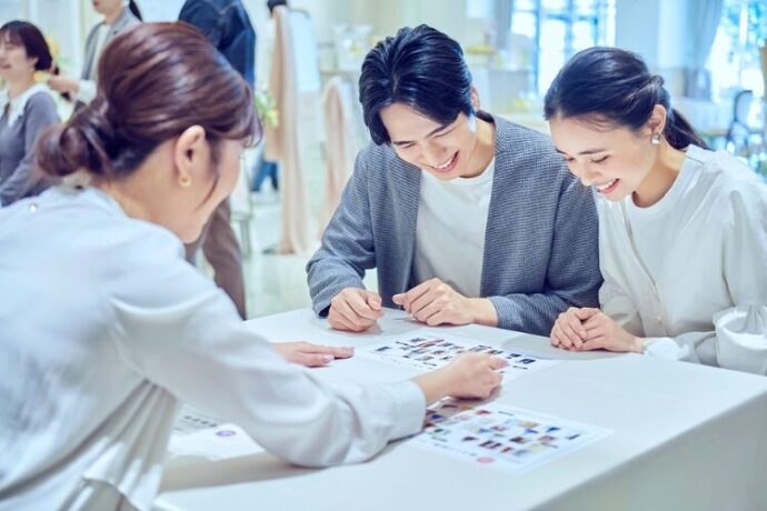 プランナーから割引などの特典の説明を受けるカップル_アニヴェルセル