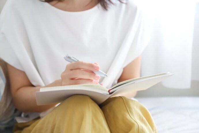 ノートに気持ちをまとめる女性の手元